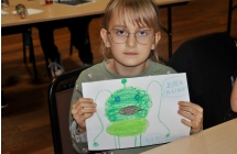 Dziewczynka w okularach ze swoją pracą plastyczną 