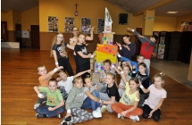 Grupa kilkunastu dzieci wraz z opiekunką na sali widowiskowej 