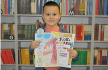 Chłopczyk trzymający prace plastyczną oraz dyplom 