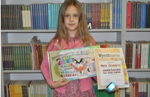 Dziewczynka z dyplomem oraz pracą plastyczną 