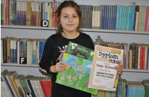 Dziewczynka trzymająca dyplom oraz prace plastyczną 