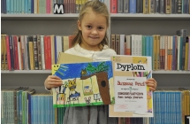 Radosna dziewczynka prezentująca dyplom oraz pracę plastyczną 