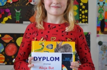 Alicja But laureatka pierwszego miejsca w kategorii klas 1 na tle prac konkursowych