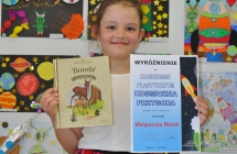 Malgorzata Misiek laureatka wyroznienia w kategorii dzieci w wieku 6-7 lat stojaca na tle prac konkursowych