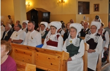 Zespol ludowy Tradycja w tradycyjnych strojach sziedzi w lawakch w trakcie mszy dozynkowej