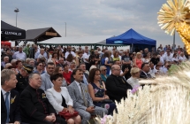 Tłum uczestników dożynek siedzi na ławkach