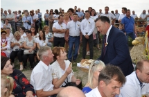 Przewodniczacy Rady Gminy cżestuje gości dożynkowych chlebem
