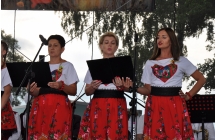 Trzy kobiety w strojach z motywem ludowym stoją przed mikrofonami