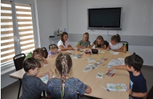 Dzieci siedza dookola stolu, koloruja malowanki