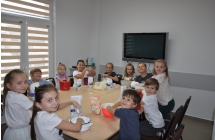 Dzieci prrzy stole, patrz a w strone aparatu, bawia sie masa sztucznego sniegu
