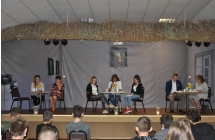Siedmioro lektorow siedzi na scenie przy stolikach