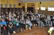 Widownia skladajaca sie z osmoklasistow wraz z opiekunami, siedza na krzeslach