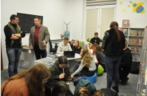 Wnetrze biblioteki, grupy mlodziezy rozwiazuja zagadki