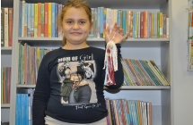 Dziewczynka w czarnej bluzie prezentuje sznurkowa laleczke