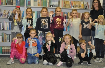 Dwanaścioro dzieci - uczestników zajęć- prezentuje swoje prace w towarzystwie instruktorki pani Pauliny