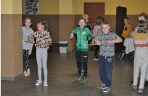 Grupa dzieci, z których troje nawija na drążki nitki 