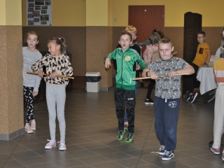 Grupa dzieci, z których troje nawija na drążki nitki 