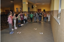 Dzieci kibicują trzem kolegom w zwijaniu nitki z doczepionymi dinozaurami