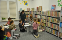 Dwa stoliki przy których siedzą dzieci wykonując pracę plastyczną, pomaga im pani dyrektor