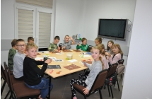 Przydużym stole siedza dzieci wykonująć pracę plastyczną