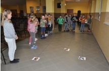 Dzieci zwijające nitki na końcu której przyczepione są papierowe dinozaury, dookoła stoją kibice
