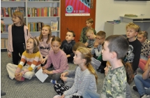 Grupa dzieci siedzi na podłodze po turecku