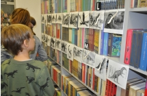 Kilkoro dzieci stoi przed ilustracjami przedstawiajacymi dinozaury