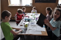 dzieciaki przy stoliczku naklejaja pomalowana kule ziemska na czarna kartke