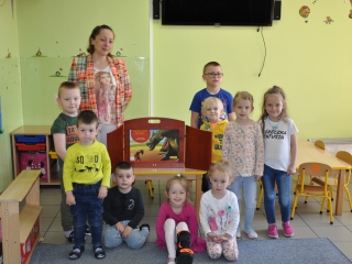 Dzieci pozuja przy teatrzyku z bibliotekarka