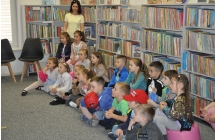 Grupa VII przedszkolakow slucha opowiesci bibliotekarki
