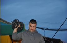 Mezczyzna trzymajacy hantel w ugietej rece