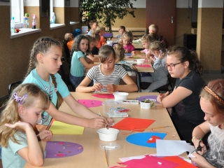 Ustawione w rzedzie stoly przy ktorych siedza dzieci