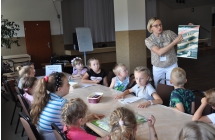 Kobieta prezentuje siedzacym dzieciom plakat