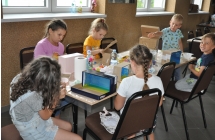 Grupa dzieci przy stole podczas ozdabiania pudelek po butach