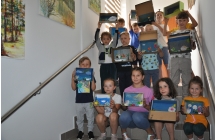 Grupa dzieci pozuje na schodach z ozdobionymi pudelkami po butach