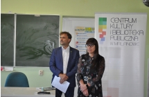 Mezczyzna i kobieta w eleganckich strojach stoja w klasie, w tle baner CKiBP w Malanowie oraz tablica szkolna