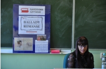 Kobieta siedzi, w tle tablica skolna na ktorej stoi