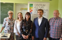 Trzy kobiety i dwoch mezczyzn pozuje do zdjecia, w tle baner CKiBP w Malanowie oraz tablica szkolna