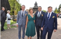 Starostowie dozynek na tle drewnianego kosciola