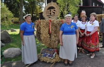 Kobiety prezentujace wysoki wieniec dozynkowy
