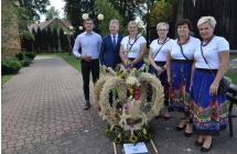 Cztery kobiety i dwoje mezczyzn prezentuja wieniec dozynkowy Gminy Brudzew