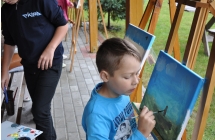 Chlopiec na tle sztalug malujacy obraz