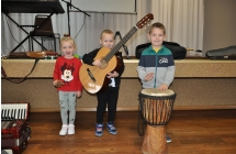 Dziewczynka i dwoje chlopcow pozujacy z gitara, bembenkiem i grzechotka