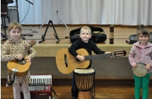 Chlopiec z gitara i dwie dziewczynki z instrumentami