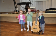 Dziewczynka z grzechotka i dwoje chlopcow z gitara i fletem