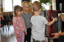 Chlopcy i dziewczynka podczas prezentacji akordeonu