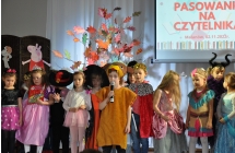 Grupa dzieci i chlopczyk mowiacy do mikrofonu