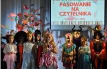 Dziewczynka mowiaca do mikrofonu w towarzystwie innych dzieci