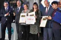 Kobieta trzymajaca nagrode w towarzystwie innych osob