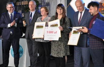 Kobieta trzymajaca nagrode w towarzystwie innych osob